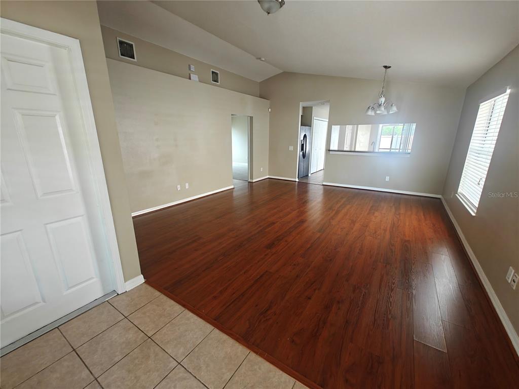 An open-concept living and dining area features dark wood flooring and a vaulted ceiling — 8225 SUMMER WOOD LANE, RIVERVIEW, FL