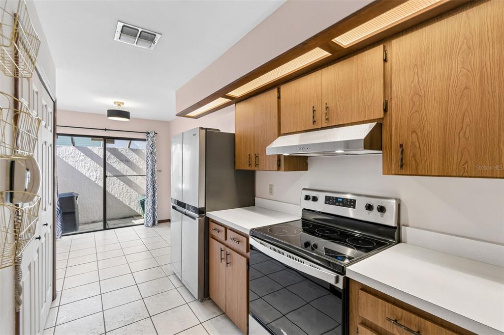 A kitchen with wood cabinets, stainless steel appliances, white countertops, and a sliding glass door — 2450 GRAND TETON CIRCLE UNIT 2450, WINTER PARK, FL