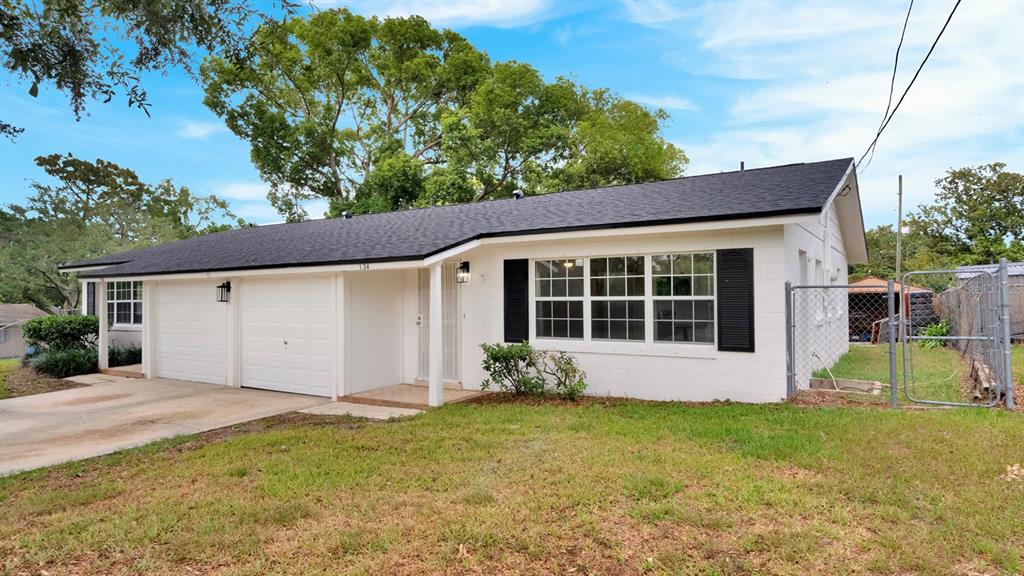 A white, single-story house with a black roof, attached garage, and a chain-link fence — 134 JEWEL DRIVE, ALTAMONTE SPRINGS, FL