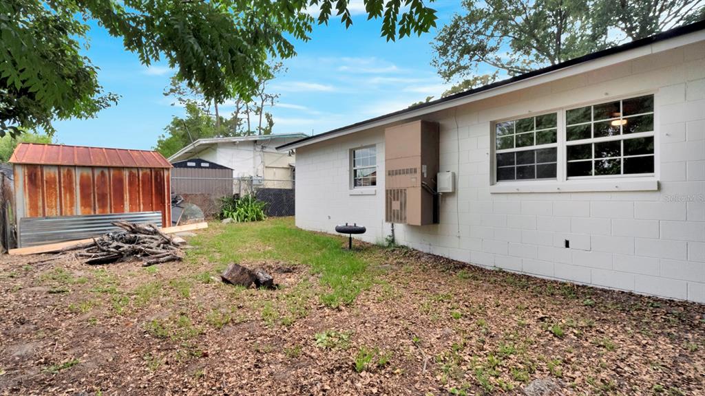 A white concrete block house exterior features a wall-mounted HVAC unit and a metal shed — 134 JEWEL DRIVE, ALTAMONTE SPRINGS, FL
