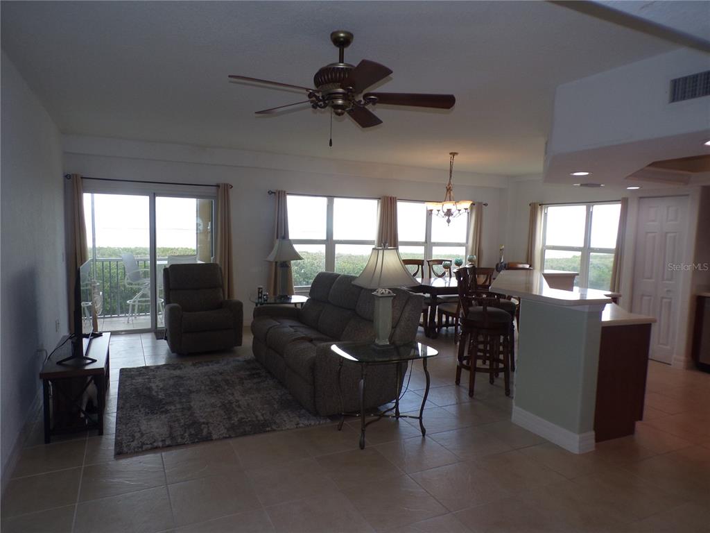 A living room and dining area with tile floors, a ceiling fan, and balcony access — 101 N MARION COURT UNIT 114, PUNTA GORDA, FL