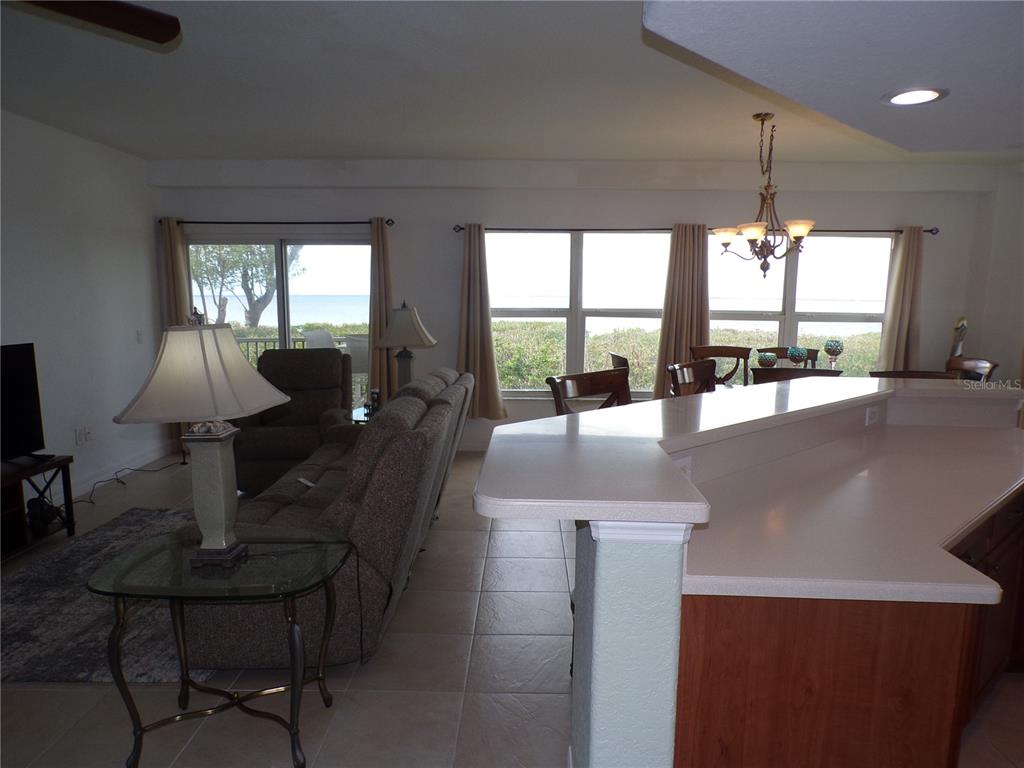 A living room and kitchen area with tile floors, a breakfast bar, and ocean views — 101 N MARION COURT UNIT 114, PUNTA GORDA, FL