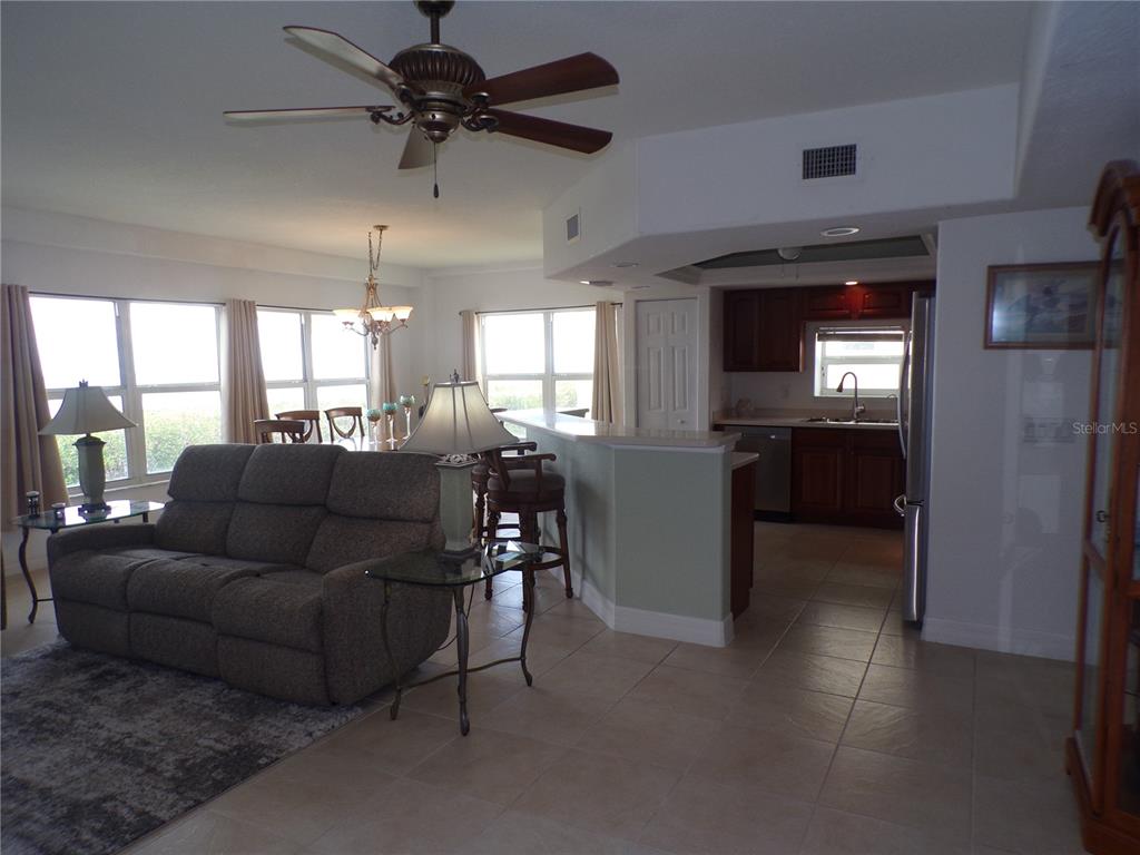 An open-concept living room and kitchen area with tile flooring and a breakfast bar — 101 N MARION COURT UNIT 114, PUNTA GORDA, FL
