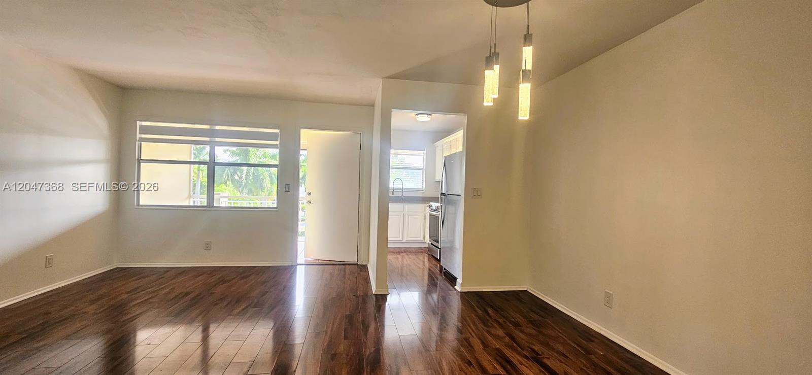 A living and dining area features dark wood flooring, a window, and pendant lighting — 300 Layne Blvd # 313, Hallandale Beach FL 33009, HALLANDALE BEACH, FL