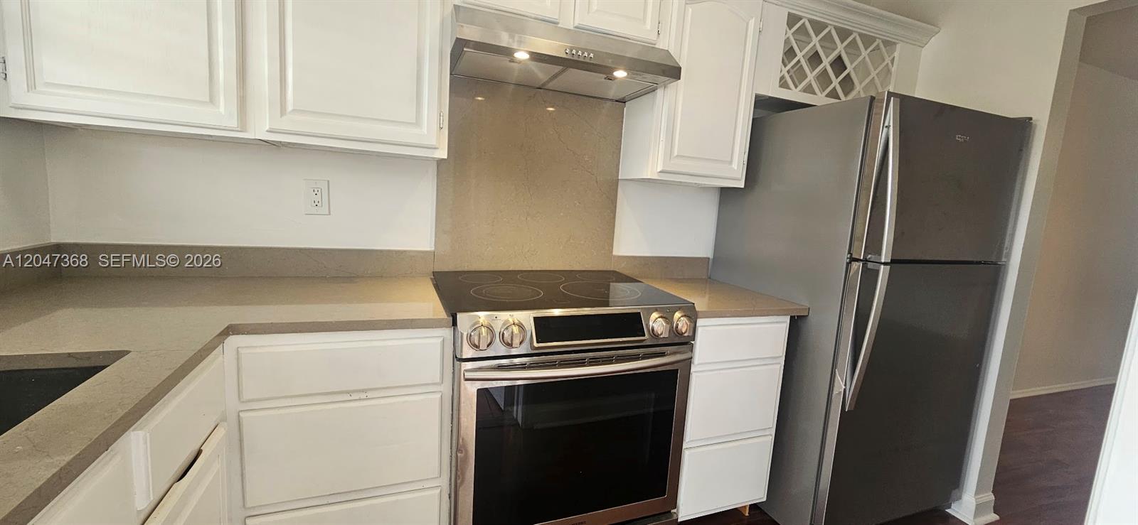 A kitchen features white cabinets, stainless steel appliances, and light-colored countertops — 300 Layne Blvd # 313, Hallandale Beach FL 33009, HALLANDALE BEACH, FL