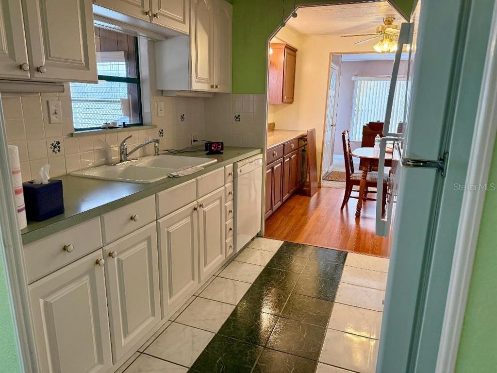 A kitchen with white cabinets, green countertops, and a tiled floor leading to a dining area — 8144 RIDGE DALE AVENUE, BROOKSVILLE, FL