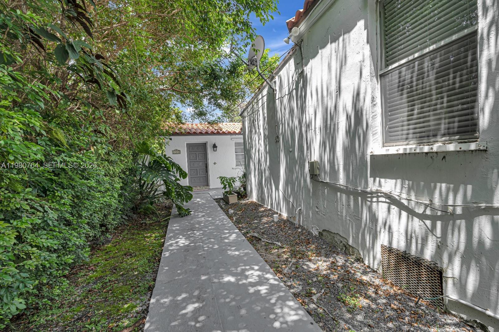 A concrete walkway leads to a white building entrance alongside a house exterior wall — 1044 SW 13th Ct # 2, Miami FL 33135, MIAMI, FL