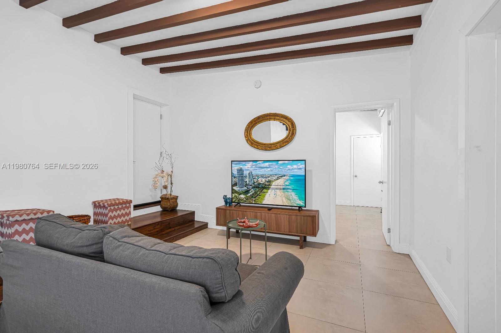 A living room features a gray sofa, a television on a console, and exposed ceiling beams — 1044 SW 13th Ct # 2, Miami FL 33135, MIAMI, FL