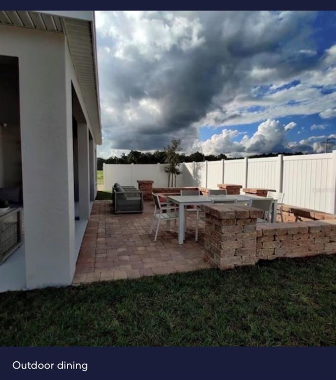 A patio with a dining set and low brick walls sits beside a white fence — 440 TISONE LANE, DAVENPORT, FL