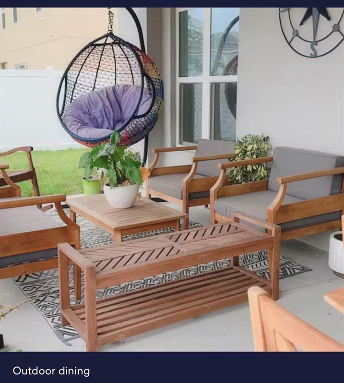 A covered patio features wooden furniture, a hanging egg chair, and a patterned area rug — 440 TISONE LANE, DAVENPORT, FL