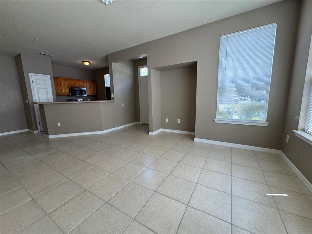 An open-concept living area features beige tile flooring, tan walls, and a kitchen breakfast bar — 9061 LEE VISTA BOULEVARD UNIT 1306, ORLANDO, FL