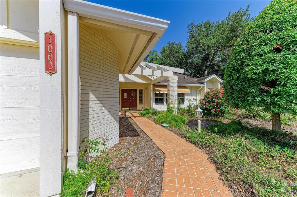 A brick walkway leads to the front entrance of a house with light-colored brick siding — 1003 83RD STREET NW, BRADENTON, FL