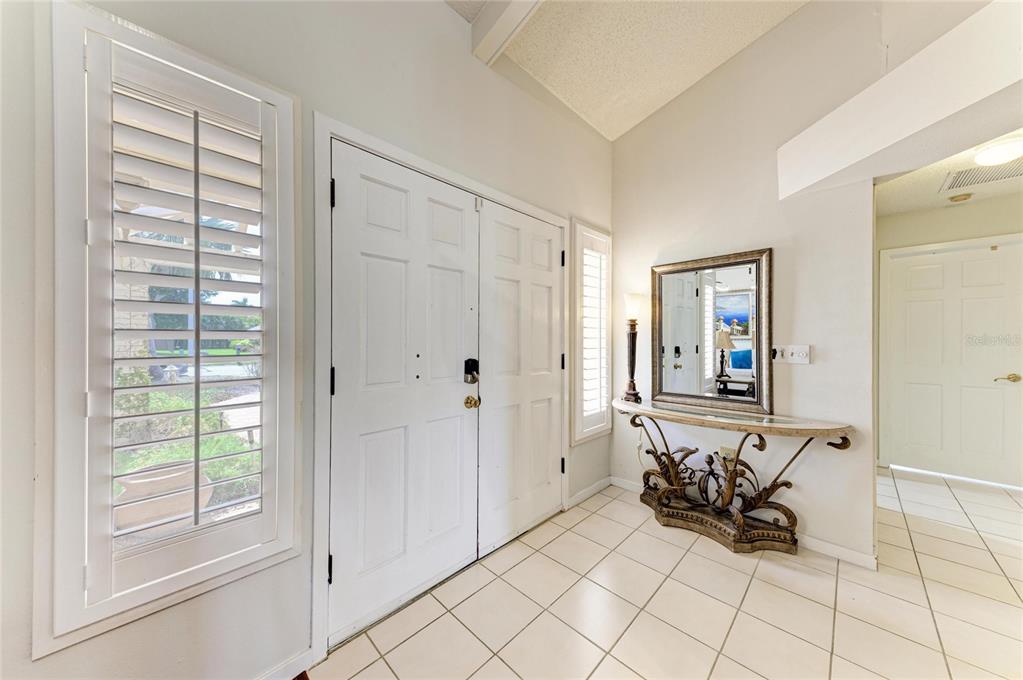 An entryway features white double doors, a tiled floor, and a decorative console table with mirror — 1003 83RD STREET NW, BRADENTON, FL