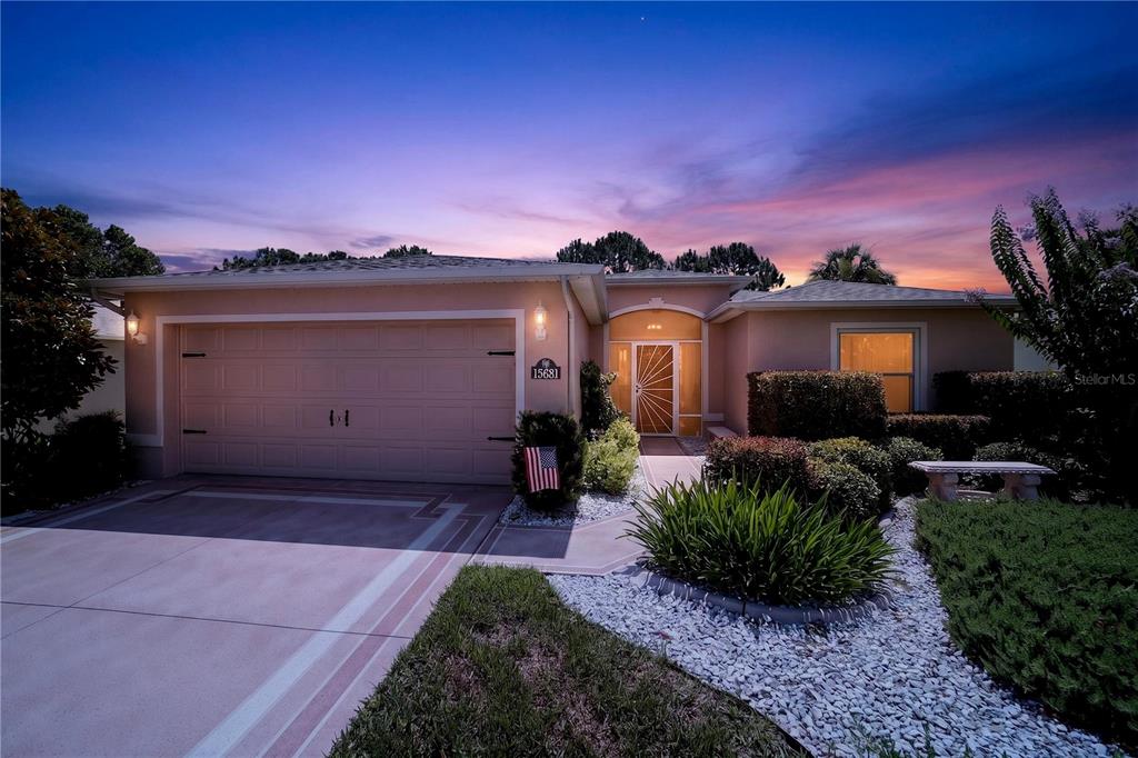 A single-story house with a two-car garage and a landscaped front yard at sunset — 15681 SW 14TH AVENUE ROAD, OCALA, FL
