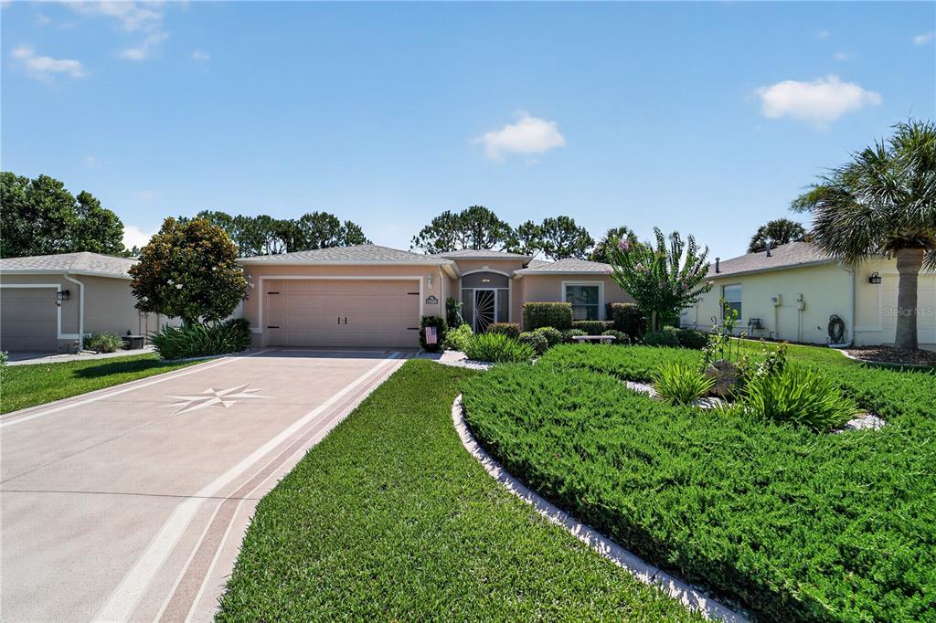 A single-story house with a beige exterior, a two-car garage, and a landscaped front yard — 15681 SW 14TH AVENUE ROAD, OCALA, FL