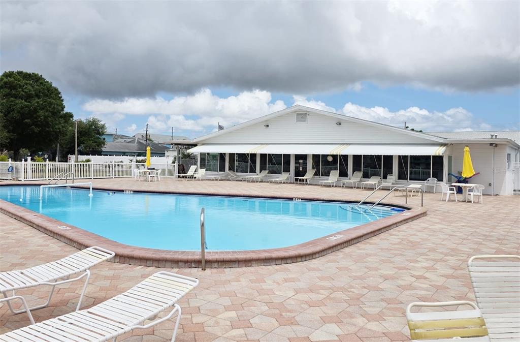 A swimming pool sits in front of a white building with a paved deck — 6015 19TH STREET N UNIT 314, ST PETERSBURG, FL