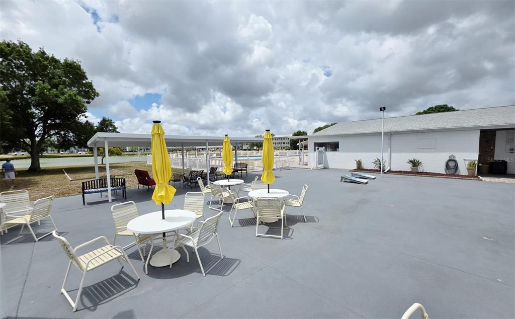 An outdoor patio area features several white tables with yellow umbrellas and chairs — 6015 19TH STREET N UNIT 314, ST PETERSBURG, FL