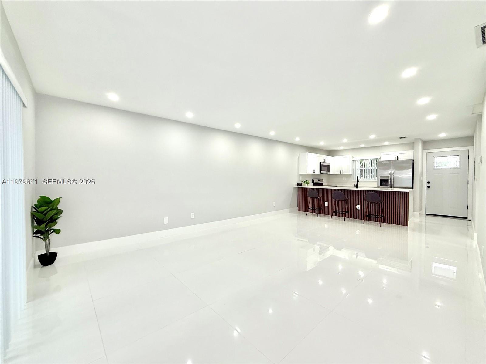 A bright, open-concept living area features white tile floors, recessed lighting, and a modern kitchen — 11240 SW 33rd Cir Pl, Miami FL 33165, MIAMI, FL