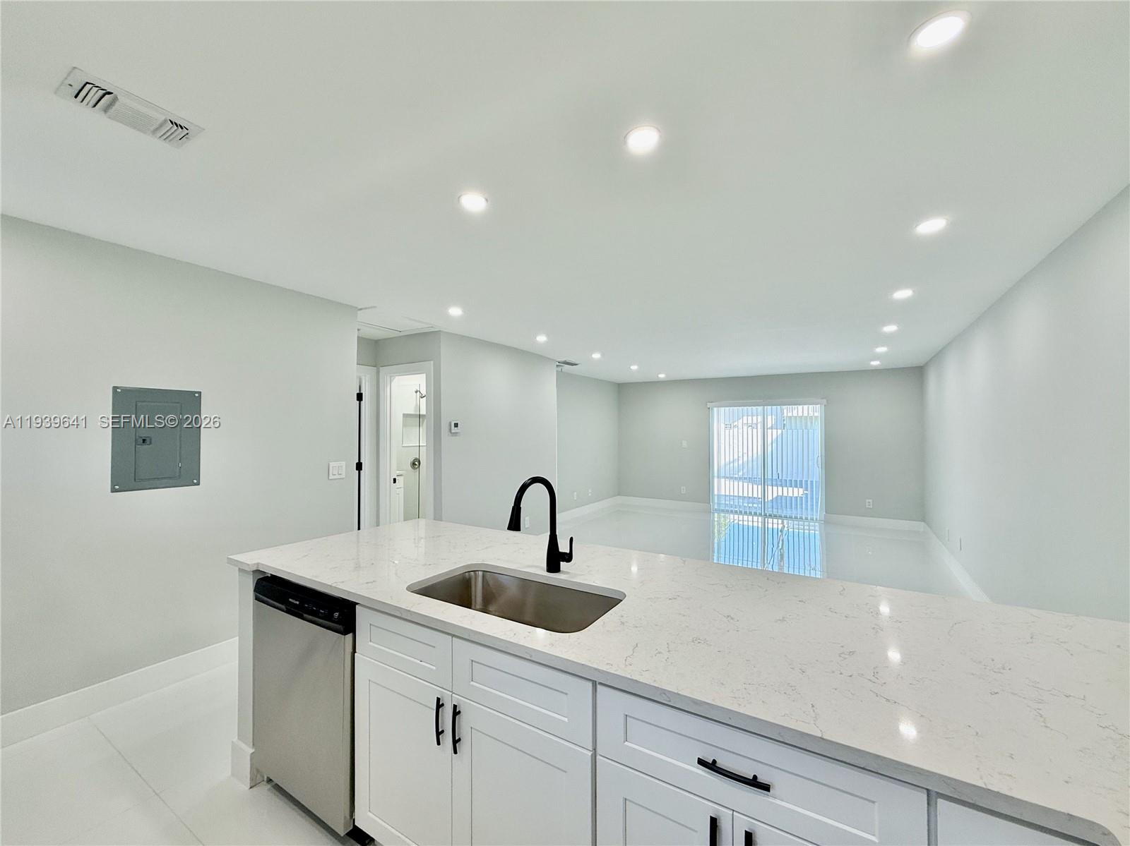 A kitchen island with a stainless steel sink and dishwasher faces an open living area — 11240 SW 33rd Cir Pl, Miami FL 33165, MIAMI, FL