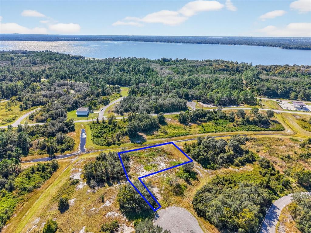 An aerial view shows a vacant, irregularly shaped lot outlined in blue near a lake — 1417 SEBRING WAY, POINCIANA, FL