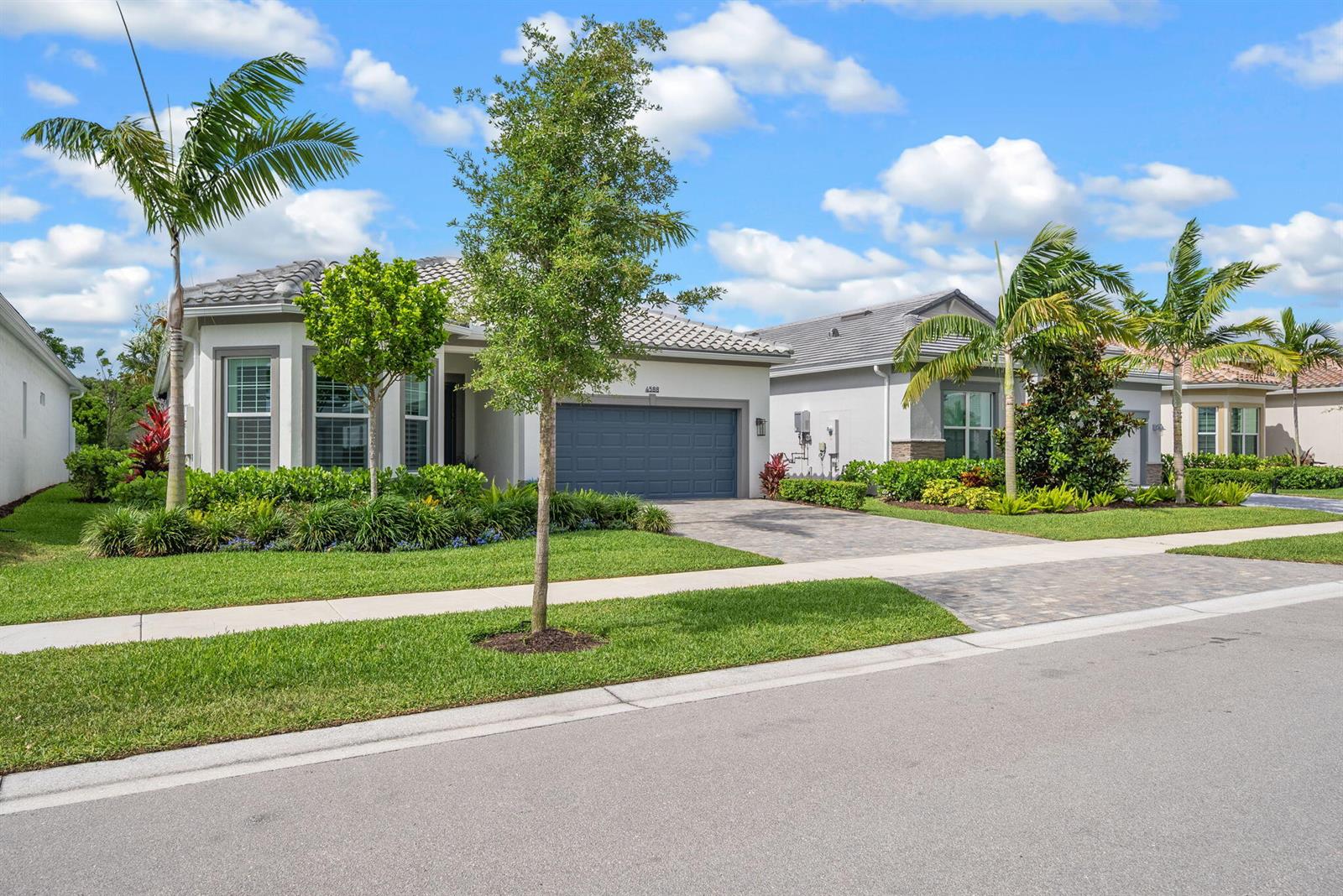 A single-story house with a gray garage and palm trees sits behind a manicured lawn — 4588 Matilda Court, Delray Beach FL 33445, DELRAY BEACH, FL