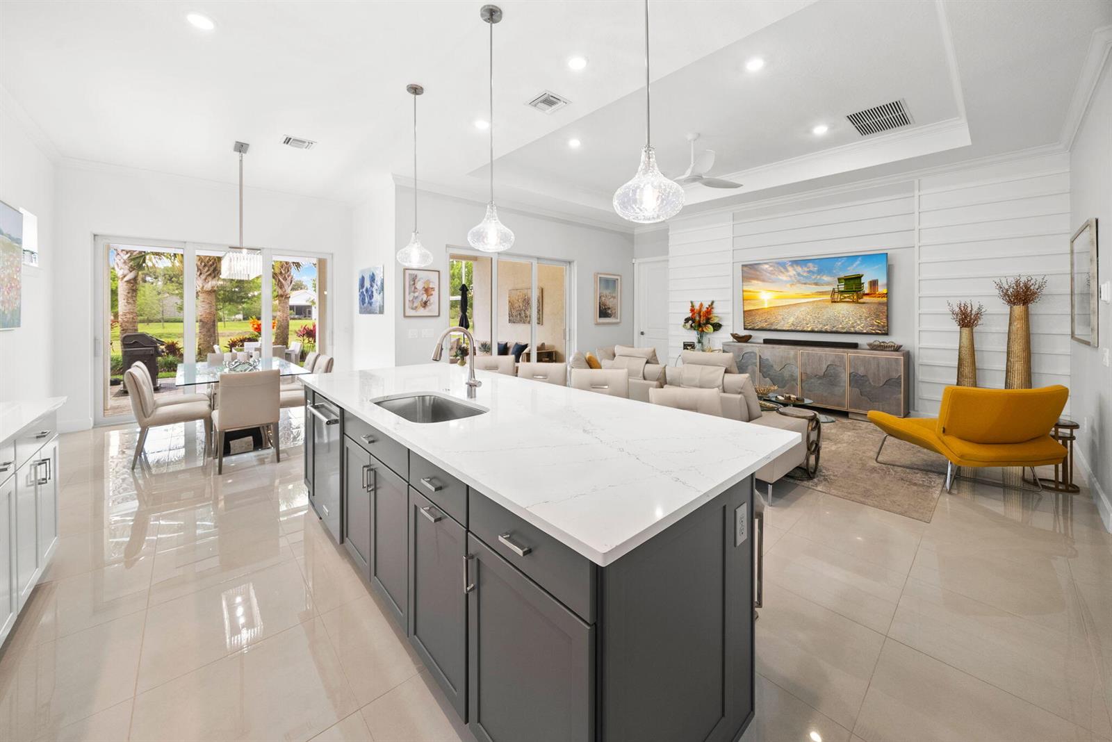 A modern open-concept kitchen and living area features a gray island, white countertops, and tile flooring — 4588 Matilda Court, Delray Beach FL 33445, DELRAY BEACH, FL
