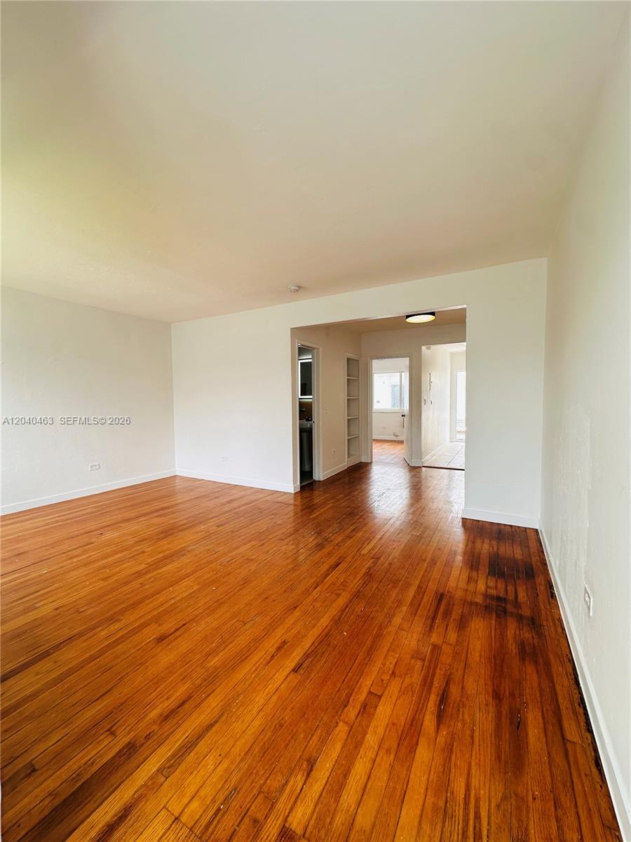 An empty room features hardwood floors, white walls, and an open doorway leading to another area — 2045 Calais Dr # 7, Miami Beach FL 33141, MIAMI BEACH, FL