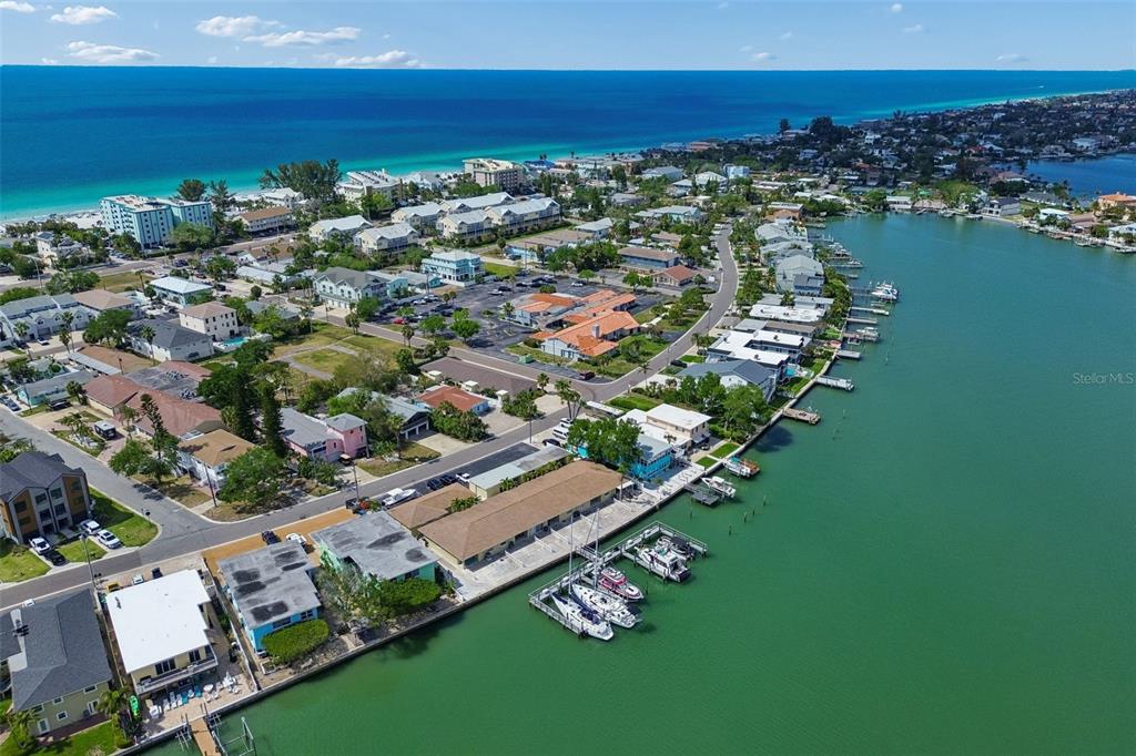 An aerial view shows a coastal neighborhood with houses, a marina, and the ocean — 2307 BAY BOULEVARD, INDIAN ROCKS BEACH, FL