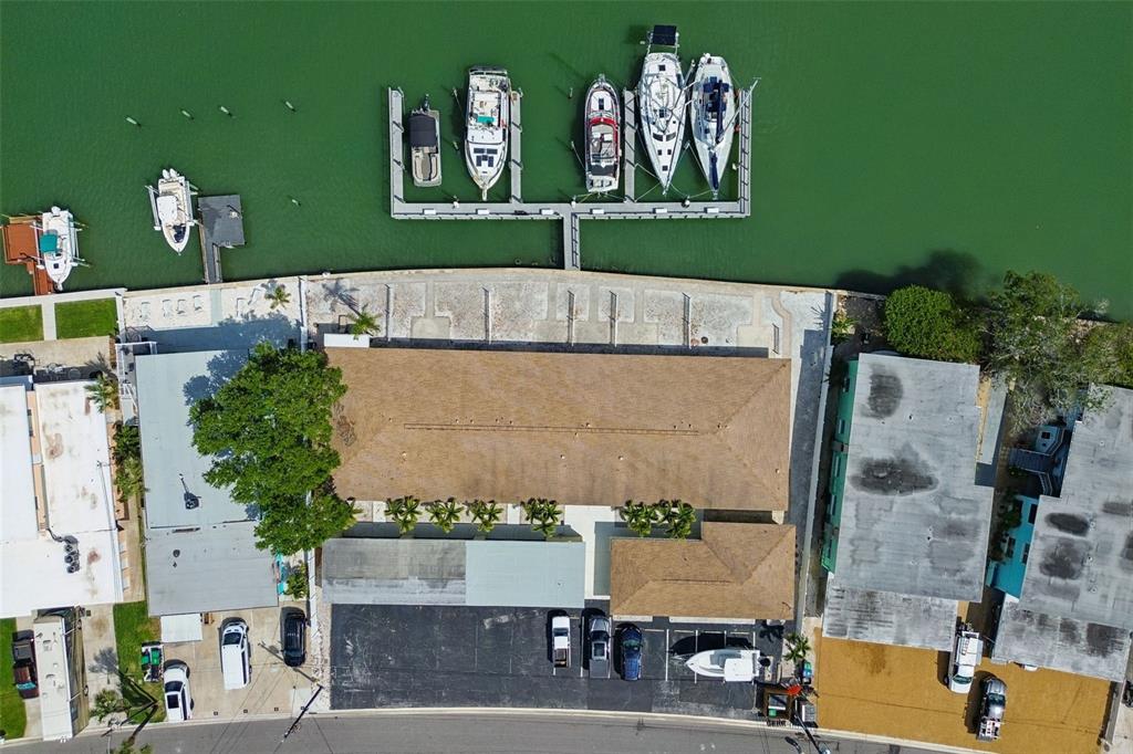 An aerial view shows a building with a brown roof, parking lot, and boat docks — 2307 BAY BOULEVARD, INDIAN ROCKS BEACH, FL