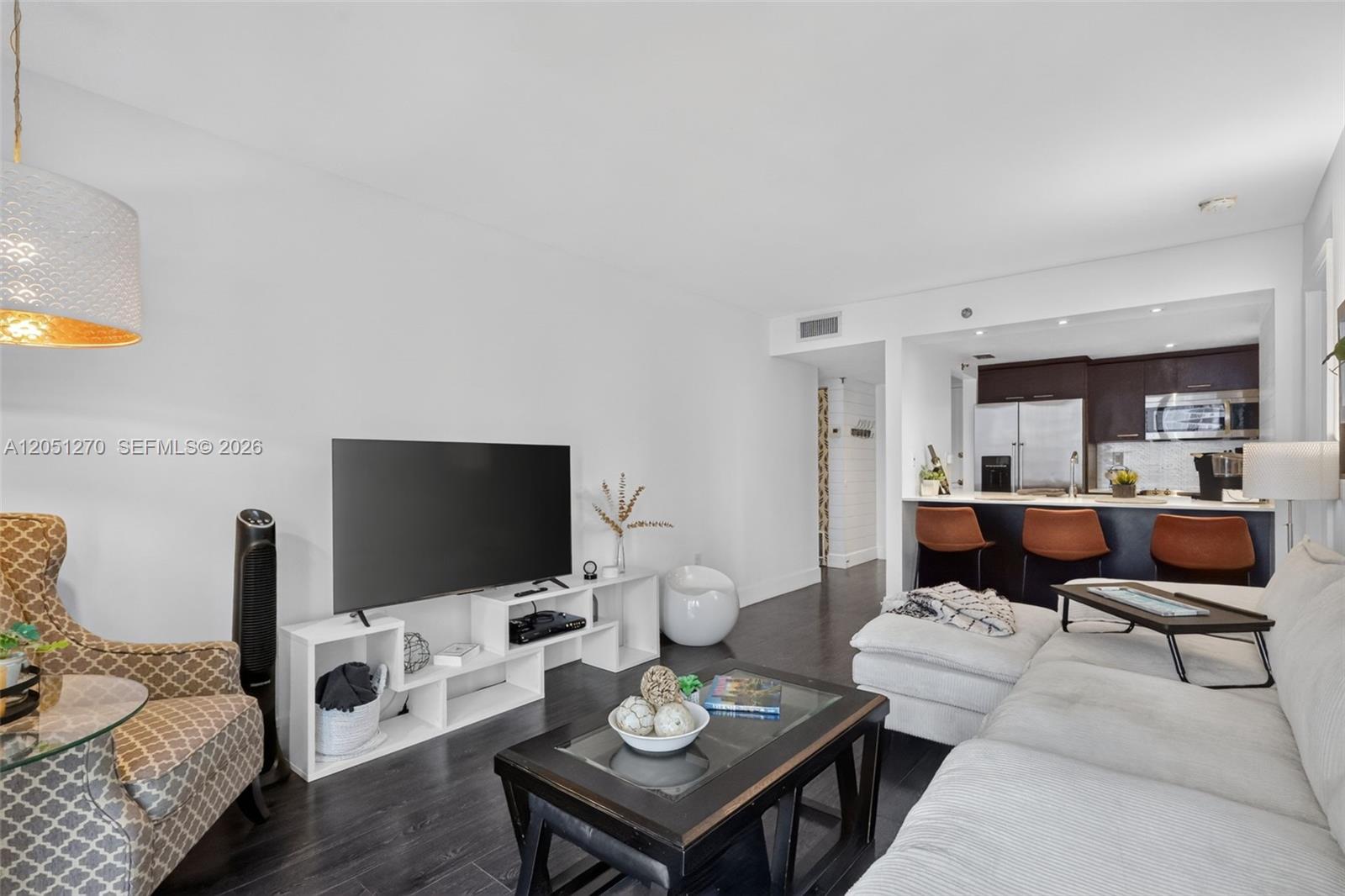 A living room features dark wood floors, a white media console, and an open kitchen — 850 N Miami Ave # 1202, Miami FL 33136, MIAMI, FL
