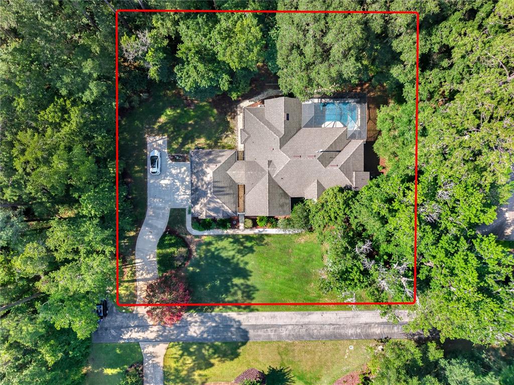 An aerial view shows a house with a pool and driveway surrounded by dense trees — 11415 NW 10TH LANE, GAINESVILLE, FL