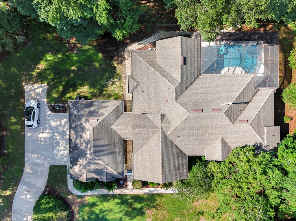 An aerial view shows a house with a shingled roof, a pool enclosure, and driveway — 11415 NW 10TH LANE, GAINESVILLE, FL
