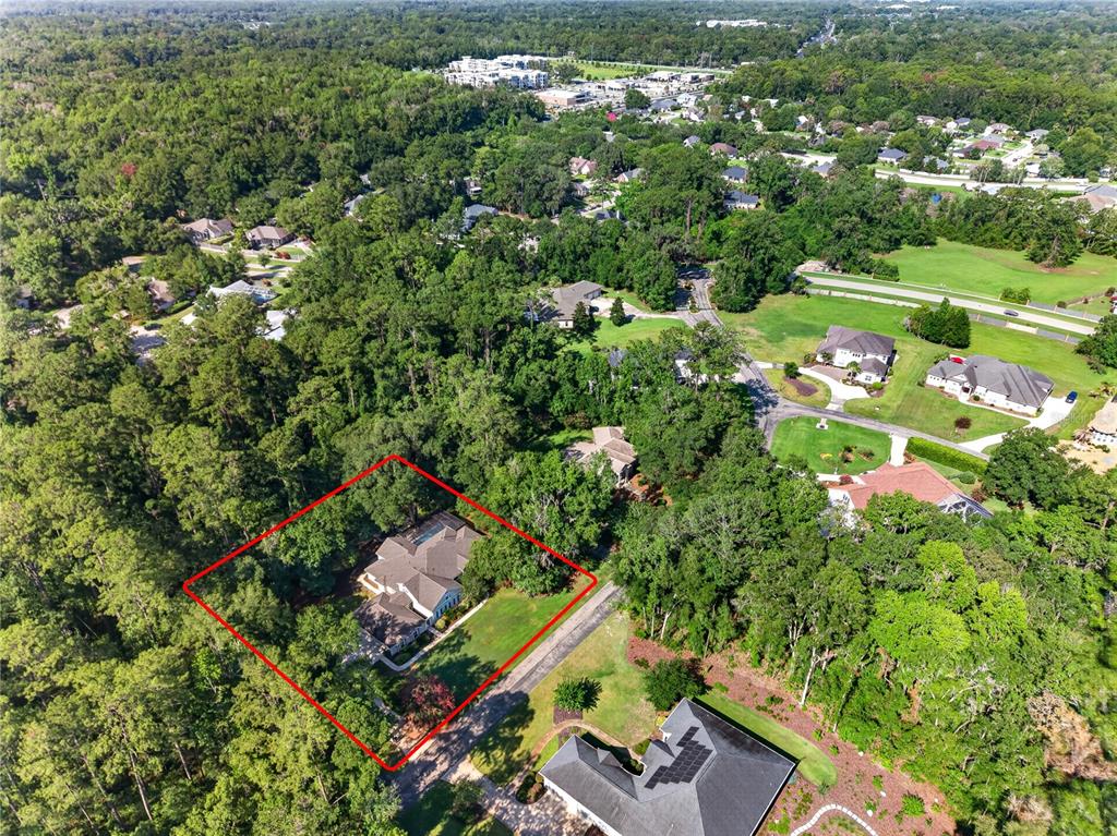 An aerial view shows a single-family home surrounded by dense trees and a red outline — 11415 NW 10TH LANE, GAINESVILLE, FL
