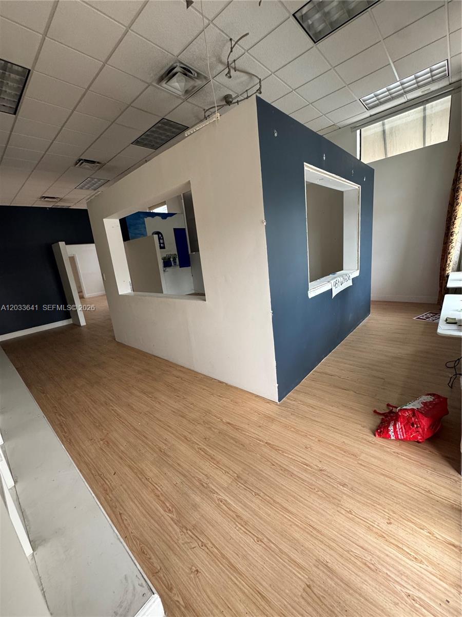 A commercial interior features wood-look flooring, a central partition wall with cutouts, and drop ceilings — 2 S Federal Hwy, Dania Beach FL 33004, DANIA BEACH, FL
