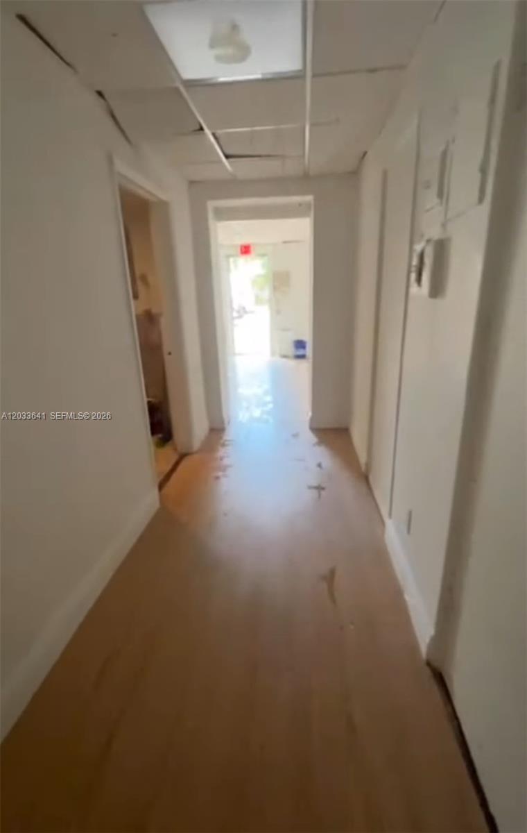 A narrow hallway with light wood-look flooring leads toward an exit door — 2 S Federal Hwy, Dania Beach FL 33004, DANIA BEACH, FL