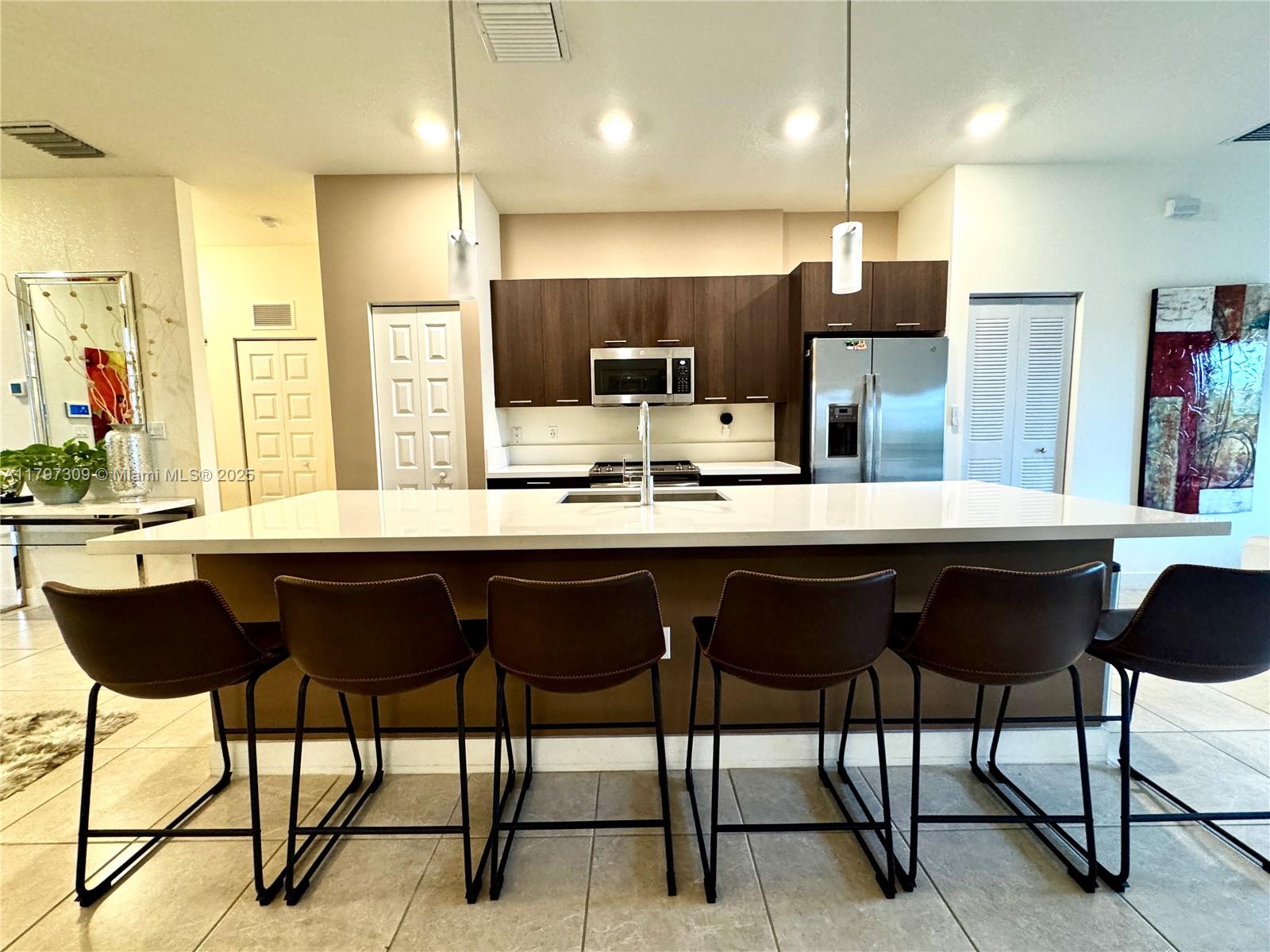 A kitchen features a large white island with six brown stools and dark wood cabinetry — 8175 NW 104th Ave # 21, Doral FL 33178, DORAL, FL