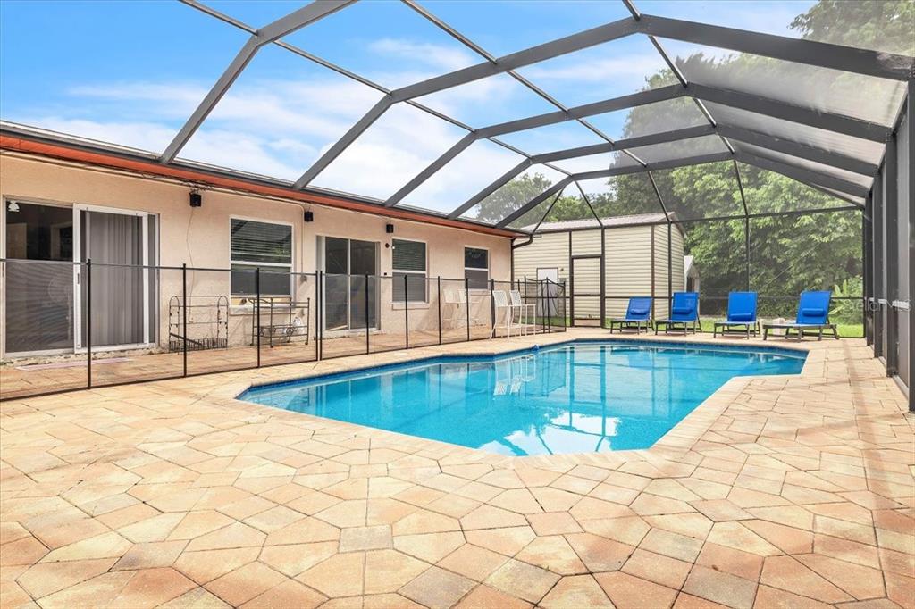 A screened-in patio features a rectangular swimming pool, paver decking, and a safety fence — 1655 DANIELS DRIVE, NORTH FORT MYERS, FL