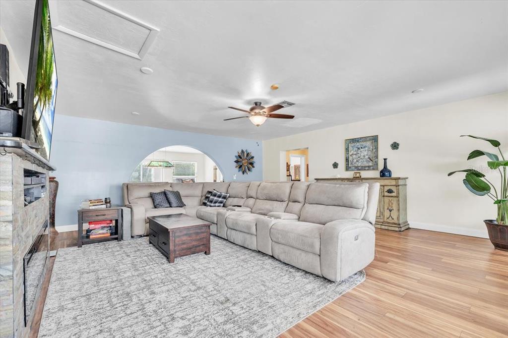 A living room features a large sectional sofa, a stone fireplace, and wood flooring — 1655 DANIELS DRIVE, NORTH FORT MYERS, FL