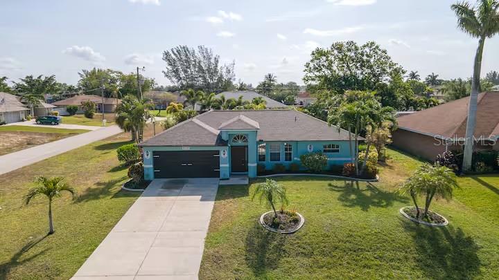 An exterior view of a single-story teal house with a dark roof and concrete driveway — 2705 SW 11TH PLACE, CAPE CORAL, FL