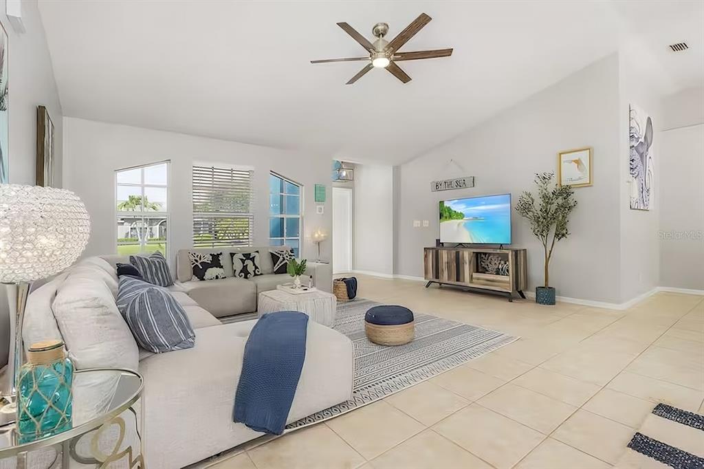 A bright living room features a sectional sofa, a television on a console, and tile flooring — 2705 SW 11TH PLACE, CAPE CORAL, FL