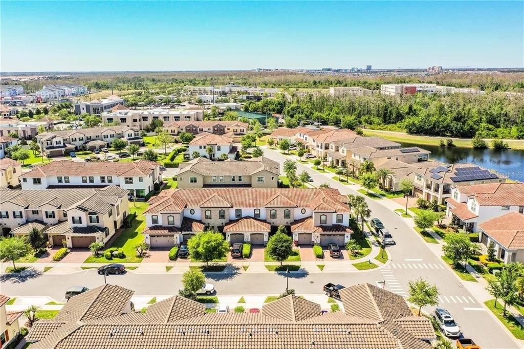 An aerial view shows a residential neighborhood with multi-story townhomes, paved streets, and green landscaping — 13886 ARCLID STREET, ORLANDO, FL