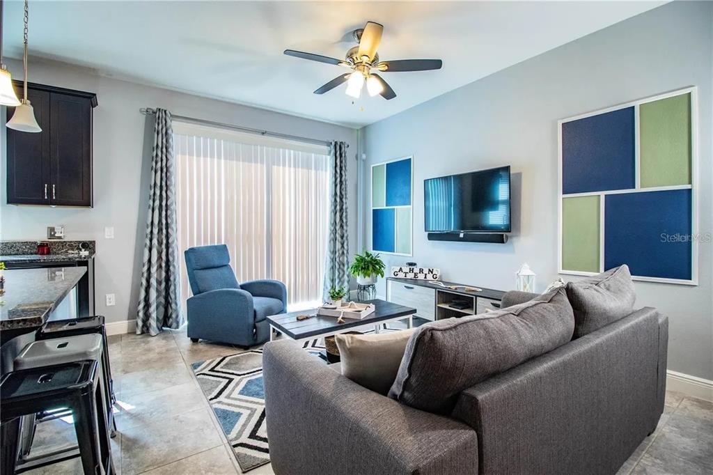 A living room features a grey sofa, blue recliner, television, and tile flooring — 13886 ARCLID STREET, ORLANDO, FL