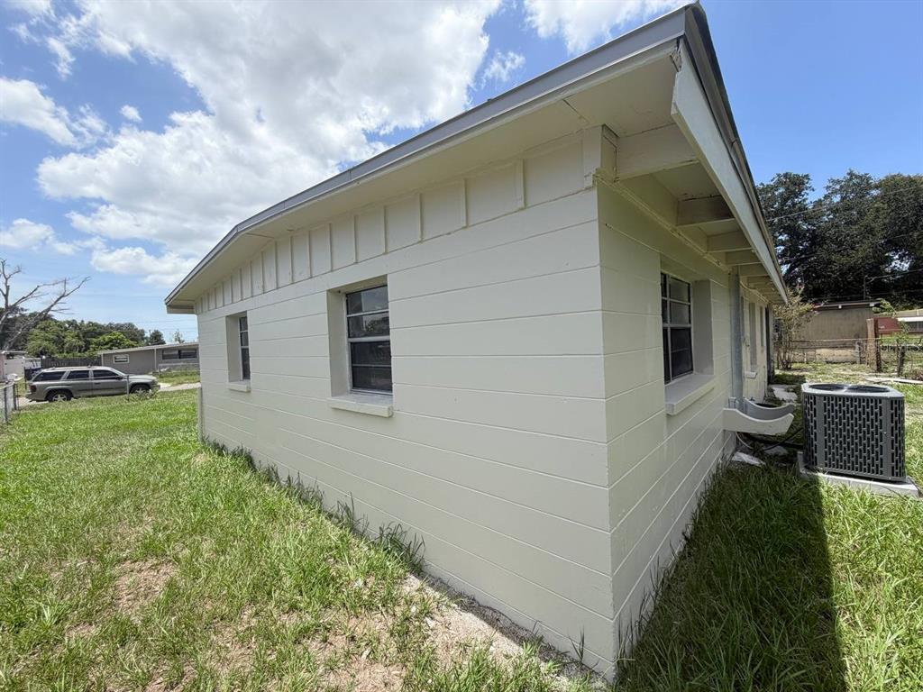 The exterior of a light-colored concrete block house features a gabled roof and windows — 1310 WARRINGTON WAY, TAMPA, FL