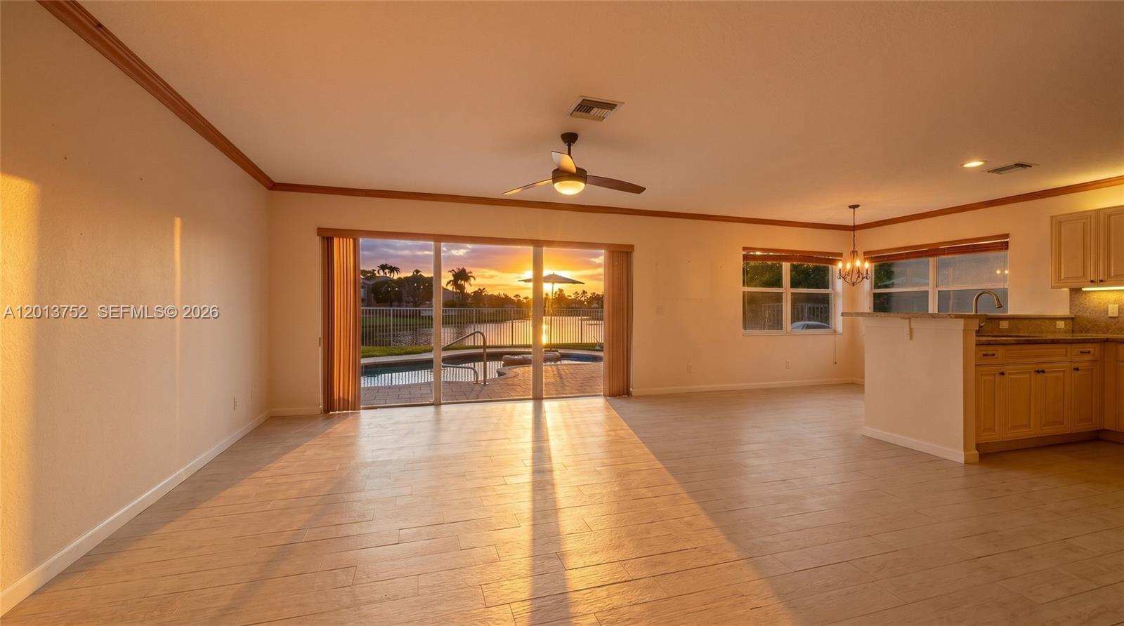 This living room features tile flooring, a ceiling fan, and sliding doors overlooking a pool — 4019 Turquoise Trl, Weston FL 33331, WESTON, FL