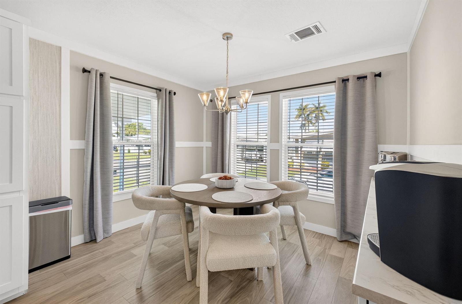 A dining area features a round wooden table, four upholstered chairs, and three large windows — 58012 Bahama Bay, Boynton Beach FL 33436, BOYNTON BEACH, FL