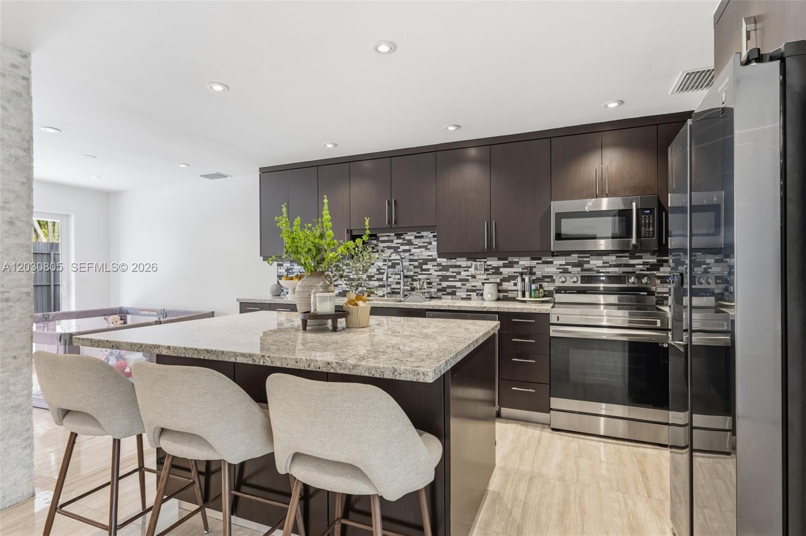 A modern kitchen features dark wood cabinets, granite countertops, stainless steel appliances, and a central island — 19040 S Saint Andrews Dr, Hialeah FL 33015, HIALEAH, FL