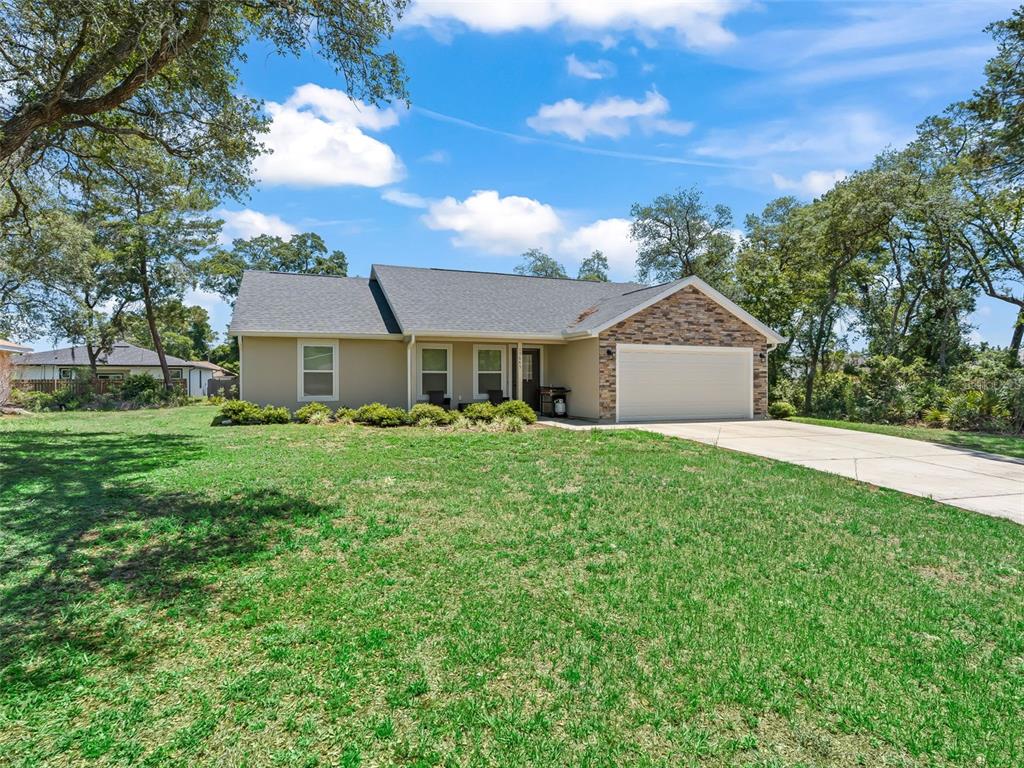 A single-story house with a stone-accented garage, tan siding, and a large front lawn — 13645 SW 39TH COURT, OCALA, FL