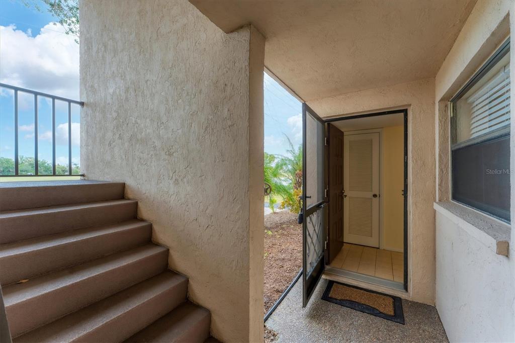 An exterior entryway features concrete stairs, a screen door, and a tiled interior floor — 104 CAPRI ISLES BOULEVARD UNIT 112, VENICE, FL