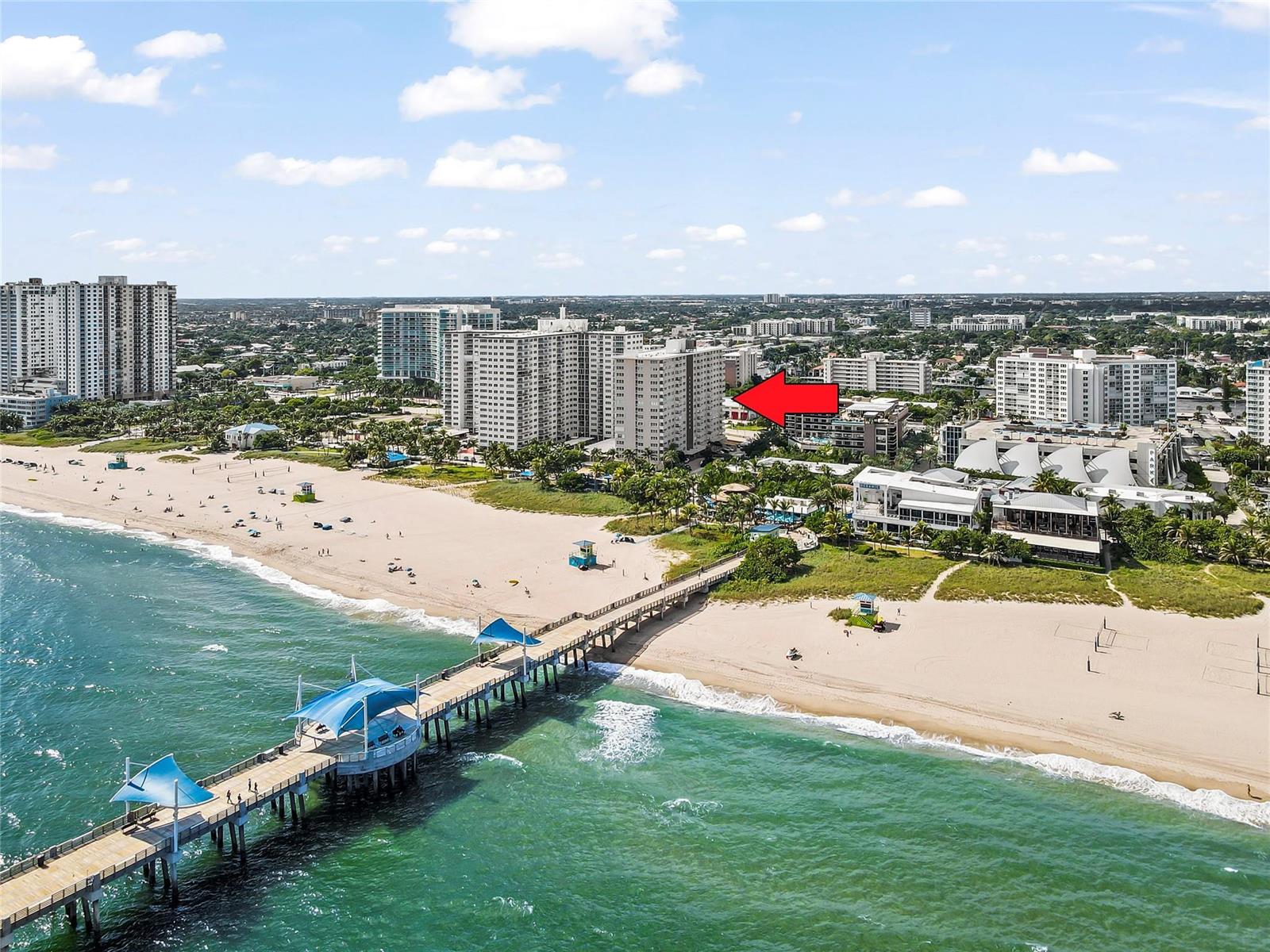 An aerial view shows a beach with a pier and several high-rise buildings nearby — 133 N Pompano Beach Boulevard # 702, Pompano Beach FL 33062, POMPANO BEACH, FL