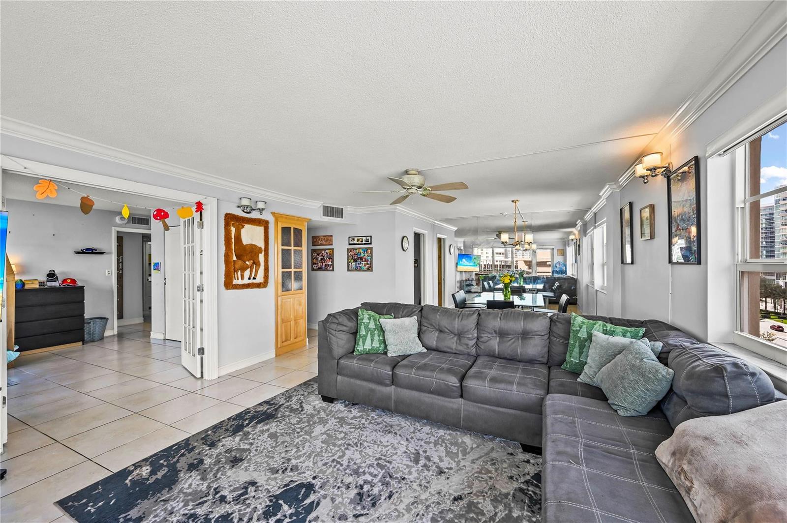 A living room features a grey sectional sofa, a patterned rug, and an adjacent dining area — 133 N Pompano Beach Boulevard # 702, Pompano Beach FL 33062, POMPANO BEACH, FL